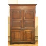 An early 19th Century joined oak press cupboard, having an angular cornice above a pair of fielded-