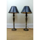 A pair of tall brass table lamps having black and gilt truncated conical shades, 48 cm to sockets,