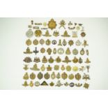A large collection of cap, collar and shoulder badges together with brass shoulder titles and