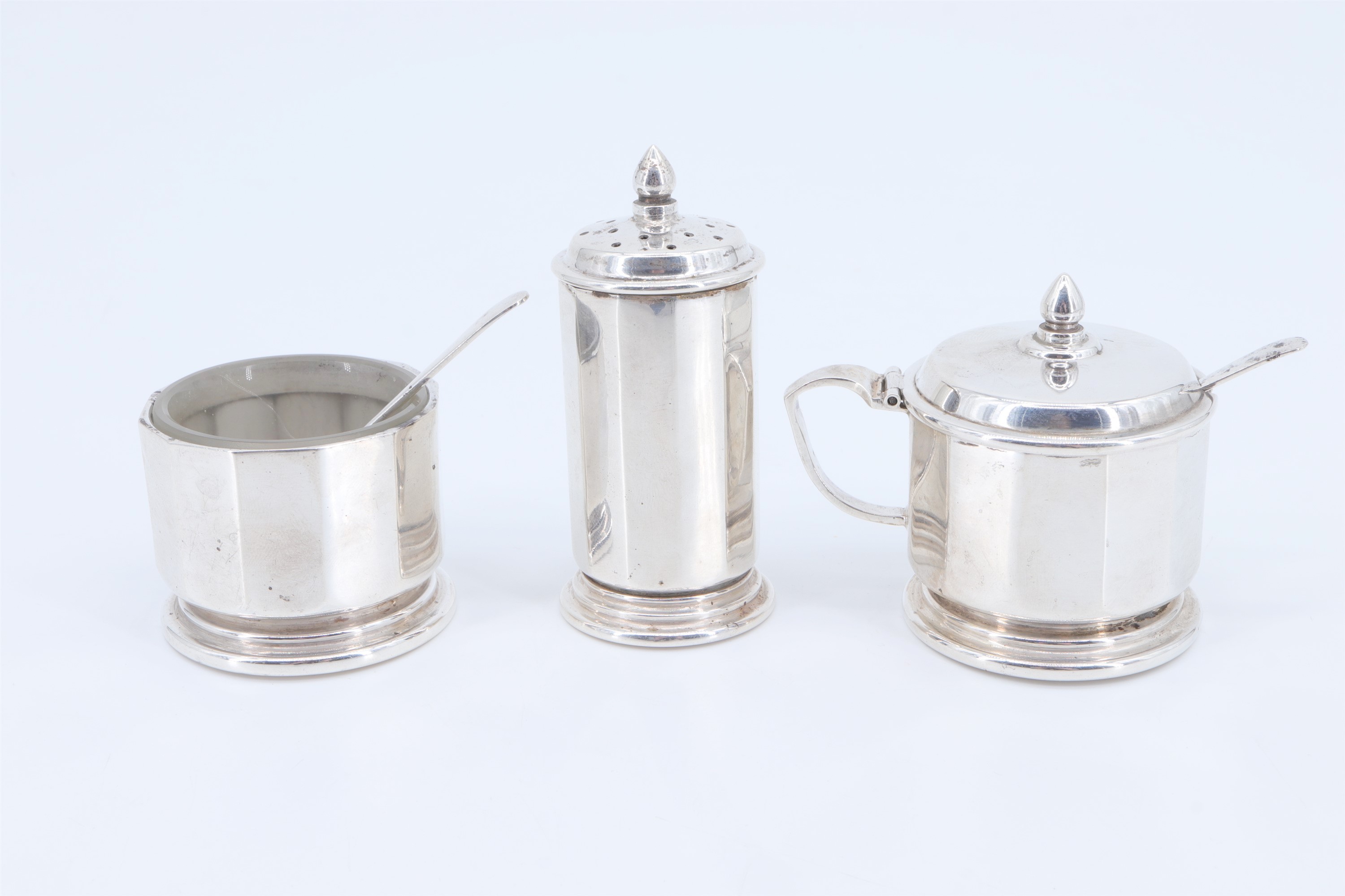 A silver three-piece condiment set, having two frosted glass liners, Hukin & Heath Ltd,
