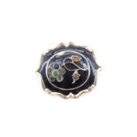 A Victorian yellow metal and enamel mourning brooch, having a raised flower set with pastes, on a