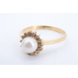 A pearl ring, the pearl of approx 6 mm framed by small claw-set facet-cut white gemstones on 18 ct