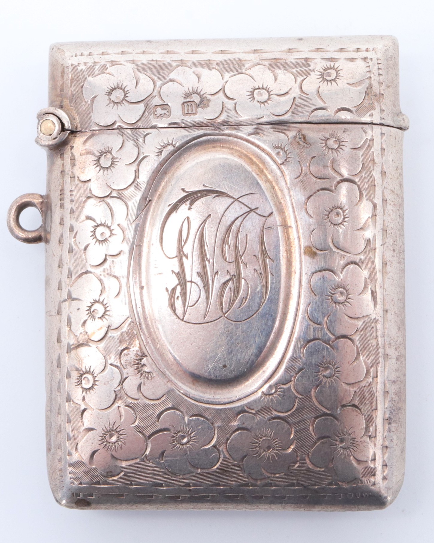 An early George V silver fob vesta case, of cushion form and decorated with engraved flowerheads