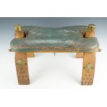 An Egyptian brass mounted camel saddle stool holding a leather seat cushion, 54 cm x 36 cm x 52 cm