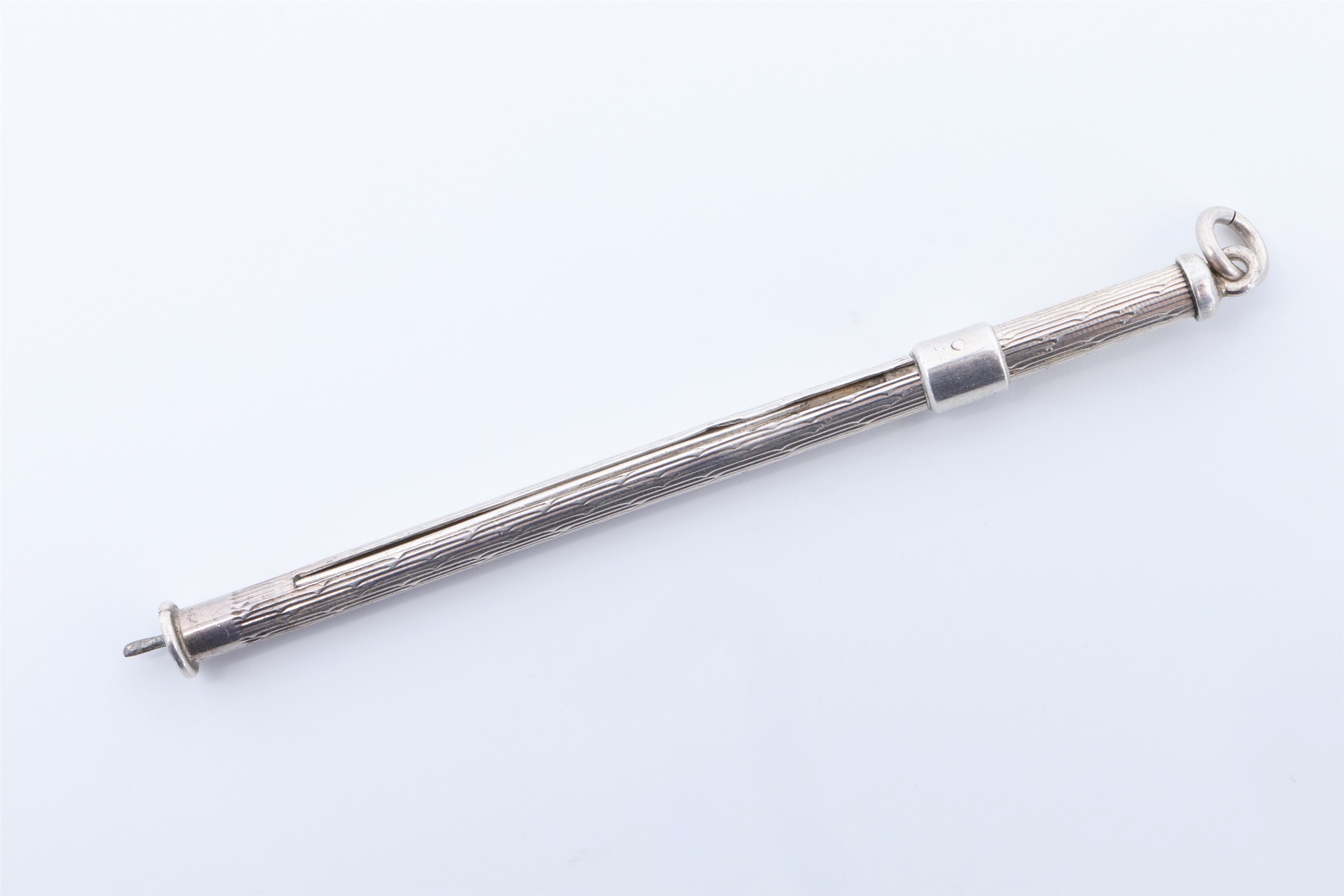 A silver cocktail swizzle stick, 7.5 cm with tines retracted
