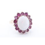 An opal and ruby dress ring, comprising an oval opal cabochon of approx 10 mm x 8 mm framed by