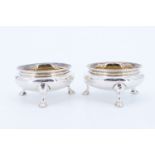 A pair of Victorian gilt lined silver salt cellars, each being of compressed form standing on