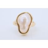 A baroque pearl finger ring, the pearl of approx 15 mm x 10 mm bezel set on a tapering 14 ct gold