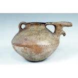 An ancient Luristan earthenware spouted vessel, of lenticular form with bridged spout and opposed