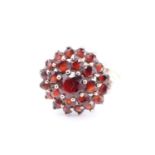 A garnet cluster ring, comprising a multitude of terraced claw-set stones set on 9 ct gold,