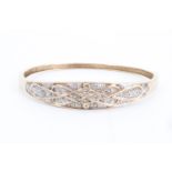 A diamond-set 9 ct gold hinged bangle, having a tapering faced with interlace framing millegrain