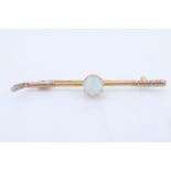 A 9 ct yellow metal bar brooch in the form of a golf club, centred by a claw-set opal cabochon, opal