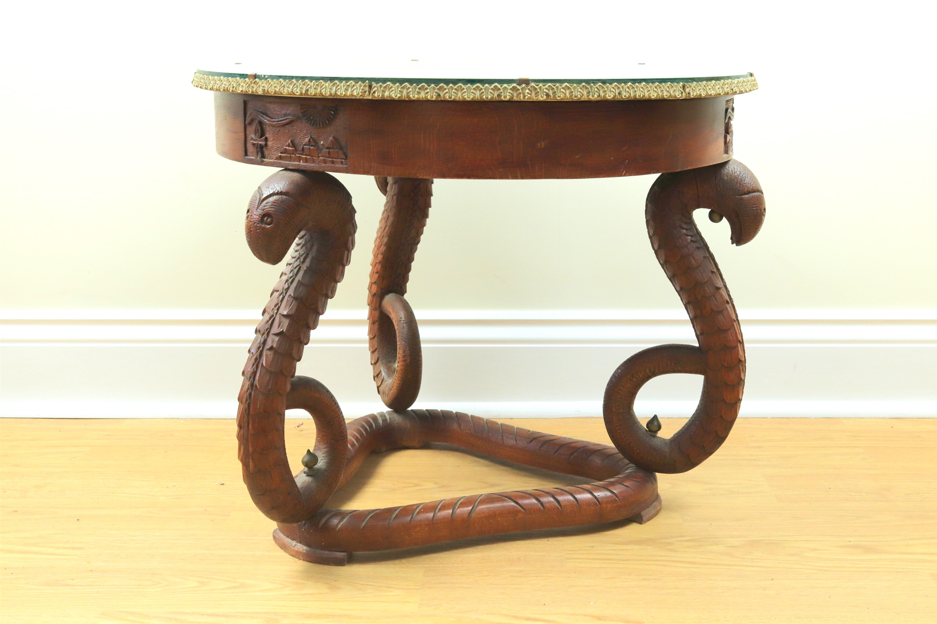 A mid-20th Century Egyptian coffee table, having a glass top enclosing a radial display of peacock