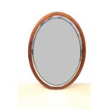 An Edwardian mahogany framed oval mirror, having cross banded stringing and bevelled glass, 94 x