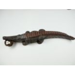 A west African carved hardwood crocodile, modelled holding a bird's nest in its jaws, 20th