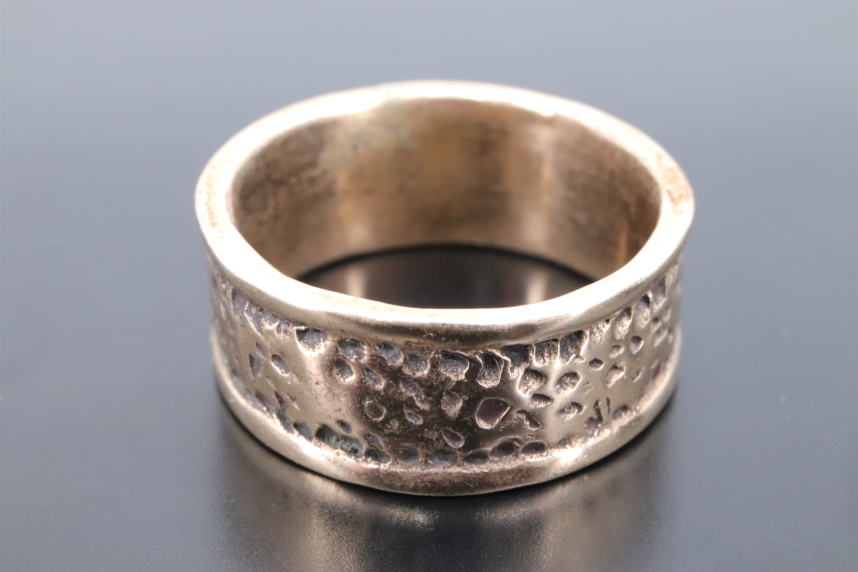A late 20th Century yellow metal wedding band, having a rusticated textured finish between ribbed