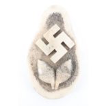 A carved antler plaque depicting a swastika and acorns, 8.5 cm x 5 cm