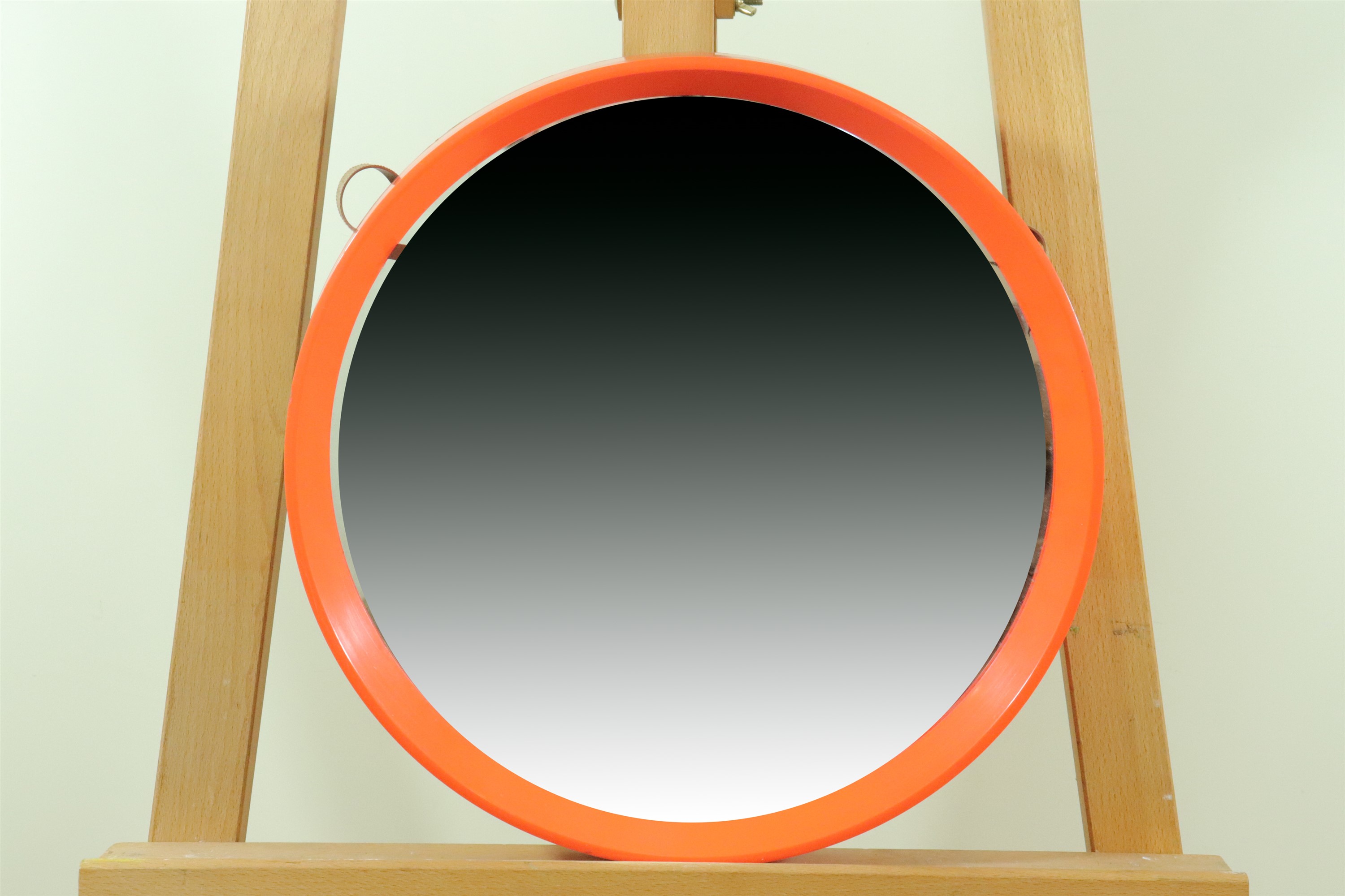 A 1970s orange plastic framed circular wall mirror, diameter 39 cm