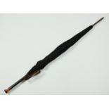 A 1920s umbrella, having an Art Deco style amber and black Lucite or Bakelite pommel and engraved