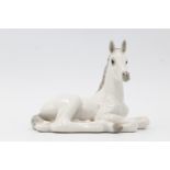 A Russian ceramic figurine of a recumbent white and grey foal, marked Lomonosov USSR, third