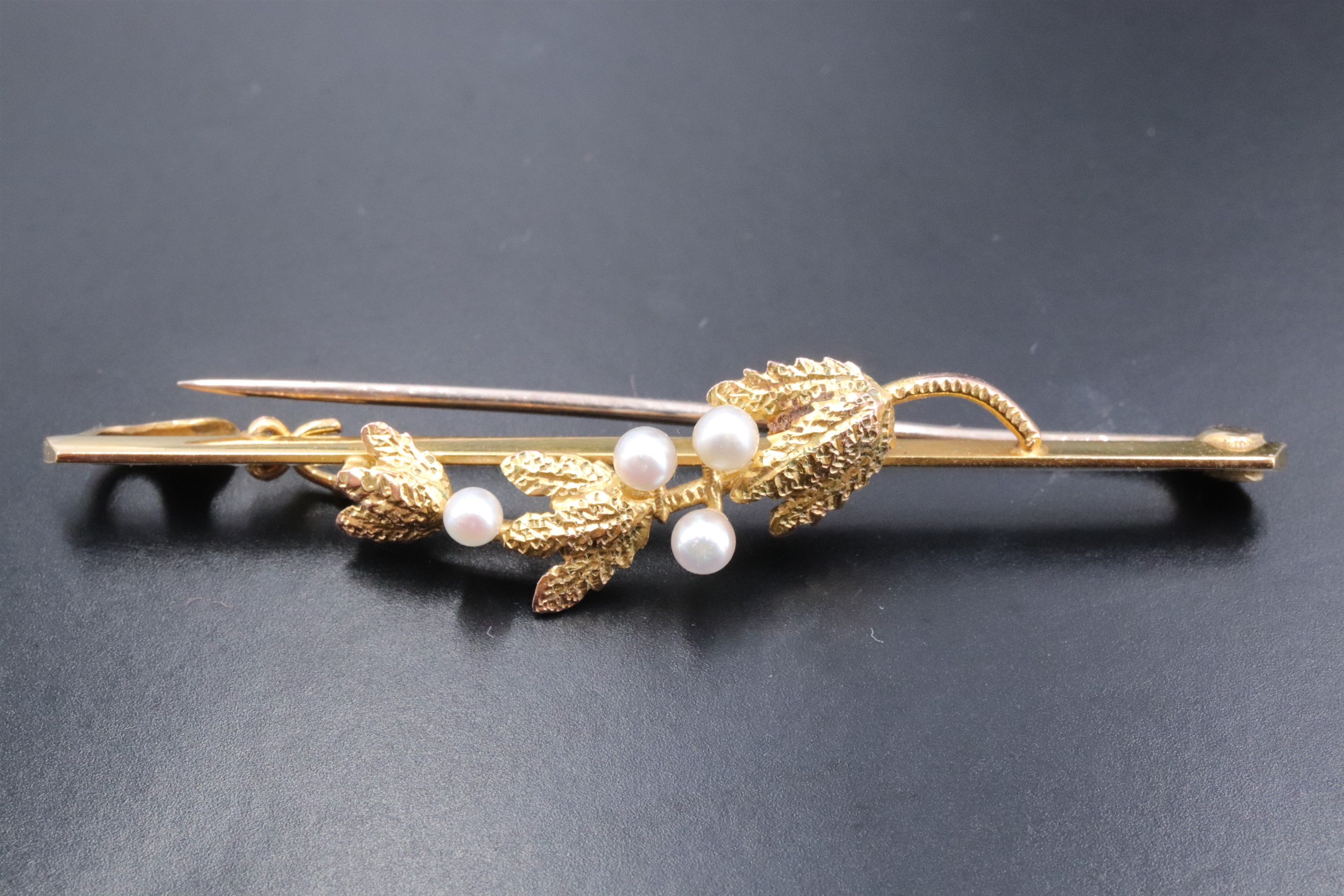 A 9 ct gold and seed pearl bar brooch, the bar faced with a pearl-set fruiting sprig, in period