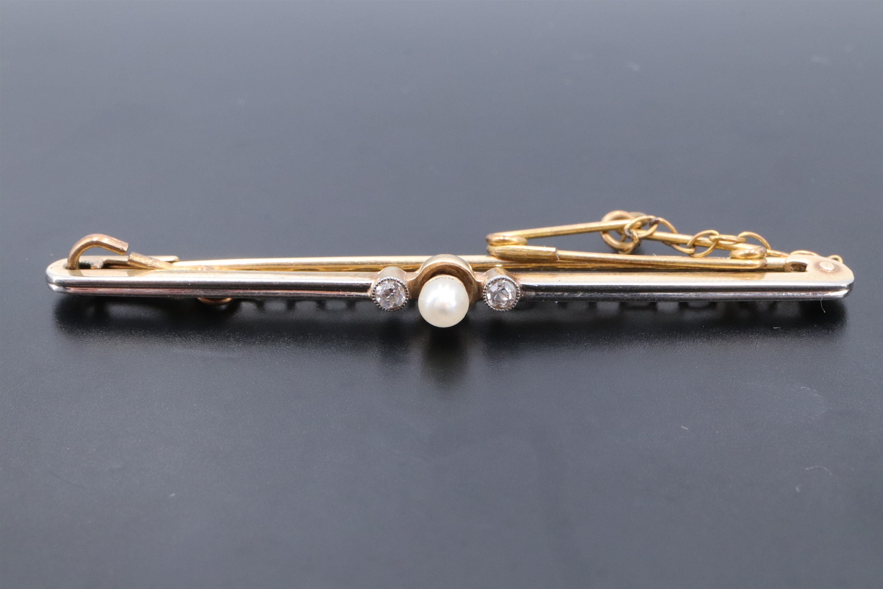 An early 20th Century seed pearl and diamond bar brooch, the small pearl cup-set above an annulus