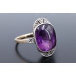 A 1930s Art Deco amethyst cabochon dress ring, the cushion shaped stone of approx 10 mm x 8 mm