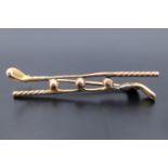 An early 20th Century yellow metal brooch in the form of an adorsed pair of golf clubs with