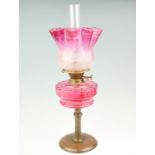 A late 19th Century copper and cranberry glass oil lamp with etched achromatising shade, with twin