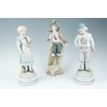 A pair of Edwardian bisque figurines, being a boy with a cat, and a girl with a basket, together