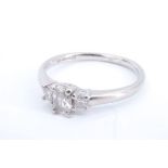 A 21st Century three stone diamond and palladium ring, having a central oval stone, 6 x 4 mm