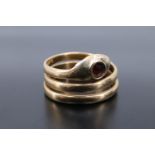 A high carat yellow metal serpent ring, set with a garnet coloured stone, 4.4 g