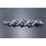 A 1920s sapphire and diamond brooch, having four pave set scrolls of five graduated old cut