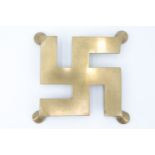 A brass trivet in the form of a swastika, 15 cm