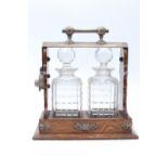 An early 20th Century oak and electroplate two decanter tantalus, [decanters a/f, key lacking], 26.5