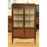 A George V glazed mahogany display cabinet, having a vitruvian scroll carved frieze above a pair