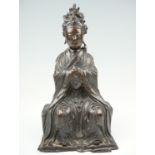 A 19th Century cast bronze figure of Guanyin, posed sitting with hands clasped and looking ahead,