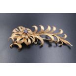 A mid 20th Century garnet set 9 ct gold floral brooch, a naturalistic spray of leaves emanating from