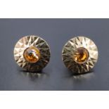 A pair of 1960s 9 ct gold sunburst ear studs, having a faceted annulus surrounding a round yellow