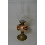 Late 19th / early 20th Century oil lamp having floral decorated pottery well, the wick adjustment