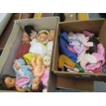 Box containing a quantity of various 20th Century injection moulded dolls and a box of dolls clothes