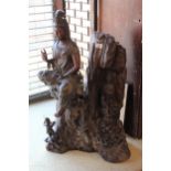 Eastern patinated bronze figure of a Goddess seated on a naturalistic root carved base with