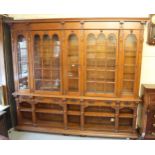 Large Victorian oak bookcase with a moulded cornice above glazed arched panelled doors and alcoves