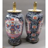 Pair of modern oriental porcelain lamp bases, decorated with panels of flowers on a blue ground,
