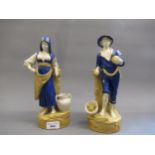 Pair of Royal Dux figures of a Continental peasant boy and girl in blue and gold shot enamel, the