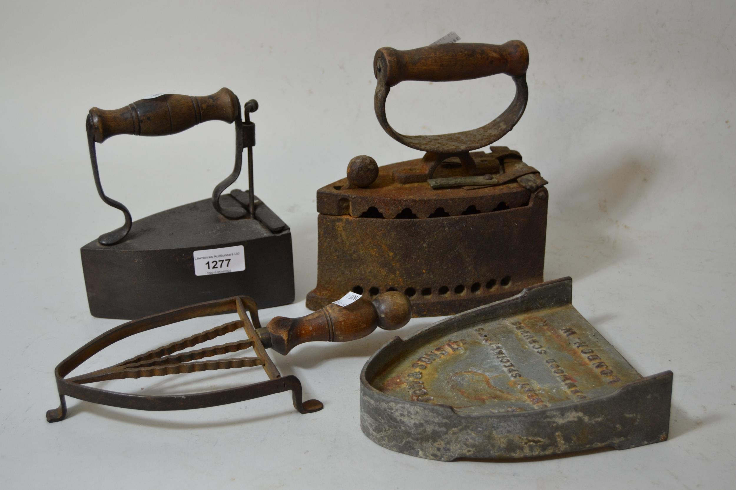 Two charcoal flatirons, together with a Hatton & Sons flat iron stand and another