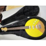 Electric guitar with a circular yellow Perspex covered body, with travel case