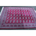Machine woven rug of Turkoman design with five rows of nine gols on a red ground, 8ft x 5ft 8ins