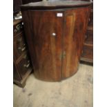 George III mahogany bow fronted two door hanging corner cabinet, 26ins wide