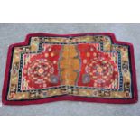 Antique Tibetan saddle rug woven with stylised floral design on a red ground with borders, 43.5ins x